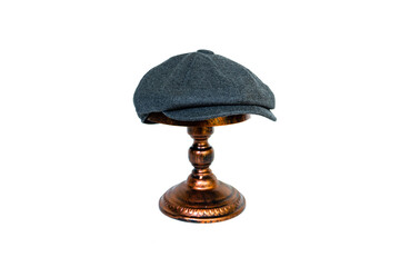 Concept photo catalog of classic newsboy cap with eight panels made of wool and warm dark grey color. Classic hat mounted on a bronze mannequin head on a white studio background