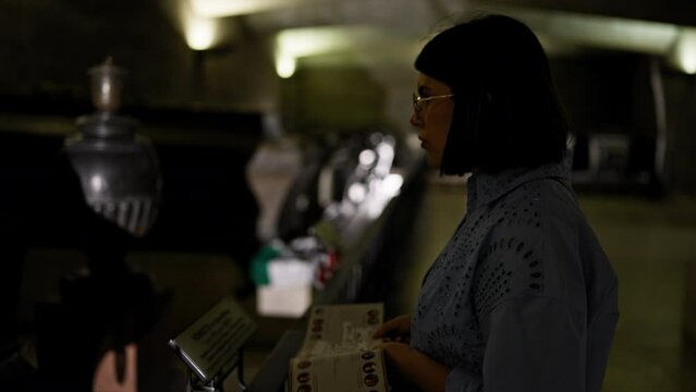 Young beautiful hispanic woman visiting crypt reading brochure at Imperial Crypt in Vienna