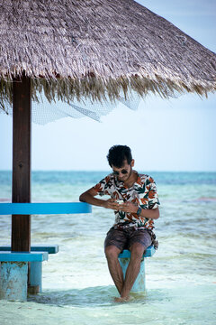 Picture of an Indian guy siting in a palm hut shade in the beaches of Maldives