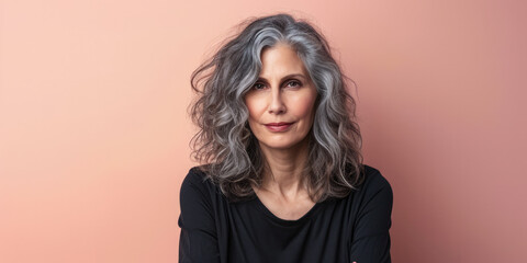 Fototapeta premium Close up of a confident middle aged woman with a peach copyspace background