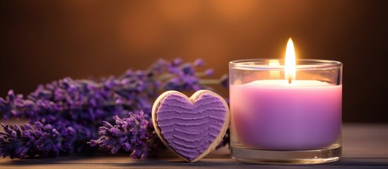 Obraz na płótnie Canvas Closeup of a lavender-scented candle in a glass and heart-shaped candle with lavender flowers burning.