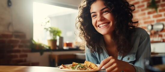 Satisfied Hispanic woman happily enjoying pizza at home. - obrazy, fototapety, plakaty