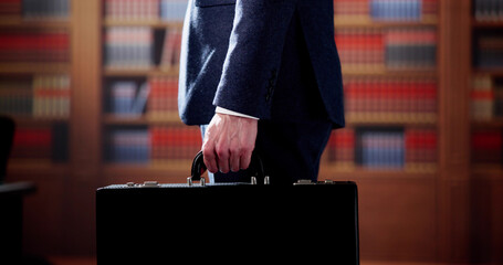 Midsection Of Lawyer Carrying Briefcase Against Bookshelf