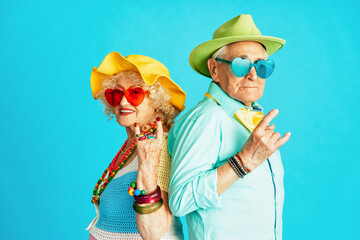 Beautiful senior old couple wearing fancy party clothes acting in studio on a colored background....