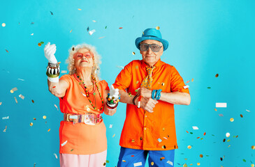 Beautiful senior old couple wearing fancy party clothes acting in studio on a colored background....