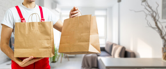 Courier holding paper bags with food, space for text. Delivery service