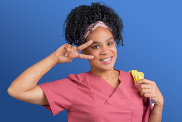 Freundliche, weibliche Reinigungskraft mit Afro beim Frühjahrsputz macht eine freundliche Geste,...