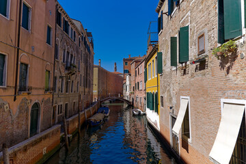 Fototapeta na wymiar Old town of City of Venice with canal and moored boats and beautiful reflections in water on a sunny summer day. Photo taken August 7th, 2023, Venice, Italy.