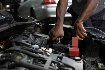 close up mechanic worker hands holding battery cable for jumping battery of a car in automobile...