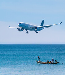 Fisherman in Longtail boats in tropical sea with Amazing big airplane landing blue sky...