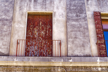 Weathered facade of historic house with wrought iron grids in front of windows at Italian City of...