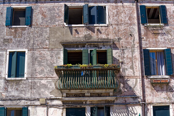 Weathered facade of historic house with wrought iron grids in front of windows at Italian City of Venice on a sunny summer day. Photo taken August 7th, 2023, Venice, Italy.