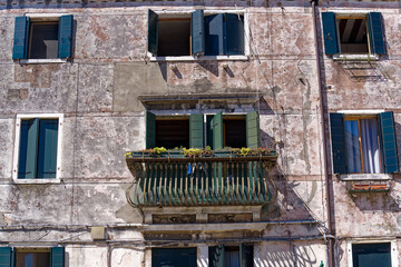 Weathered facade of historic house with wrought iron grids in front of windows at Italian City of...