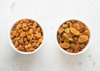 Two bowls with sweet dried green raisins on light background.Top view.