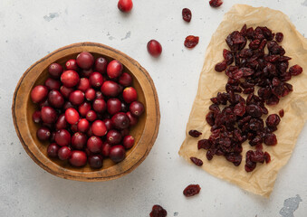 Dried red cranberry with wooden bowl of ripe cranberries on light background.Macro.