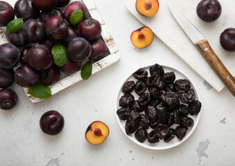 Plate with dried sweet prunes with ripe plums in wooden box on light kitchen background.Top view.