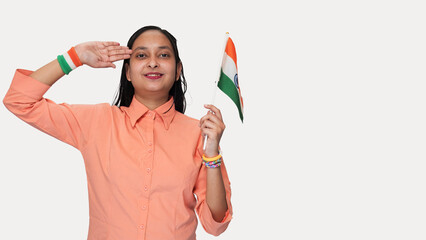 On the occasion of 26 January Young Indian girl salute to national flag, holding the national flag in her right hand and feeling patriotic, wearing a tricolor hand band, isolated on a white background