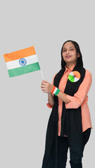 Portrait view of a young Indian lady carrying a national flag with a joyful patriotic feeling, wearing a tricolor badge and hand on the occasion of 76 Republic Day of India, isolated white background.