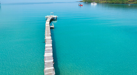 Fototapeta premium The wooden jetty leads out to the sea with blue turquoise sea water scene in summer tropical background