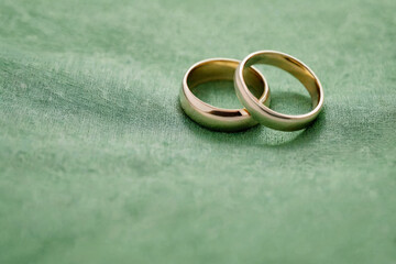 Obraz na płótnie Canvas Two simple wedding rings resting on a precious green fabric