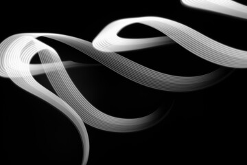 Fototapeta premium White neon curved wave of light as curls or swirl with smooth stripes on black background, pattern. Abstract background with motion light effect, light painting in New Year style.