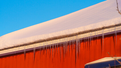 icicles hanging from a roof on a red cabin, swedish house