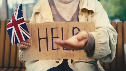 Senior woman refugee holding U.K. flag with a help sign and begging, poverty