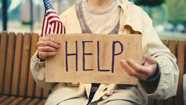 Woman refugee holding U.S. flag and help sign, asking for donations, poverty