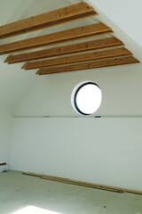 Attic of the house has wooden roof beams and white walls. Major repairs.