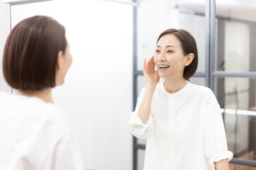 鏡を見ながら肌を触っている40代日本人女性