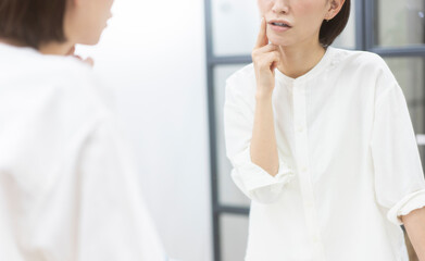 鏡を見ながら肌を見ている40代日本人女性