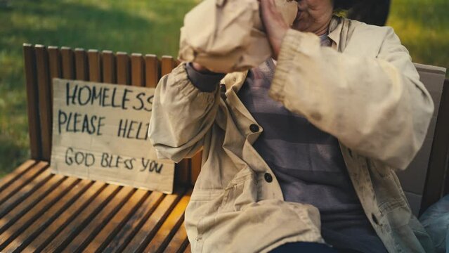 Untidy woman beggar drinking alcohol on bench, homeless please help sign