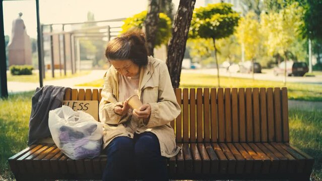 Volunteer bringing a hot meal to a senior homeless woman sitting on a park bench