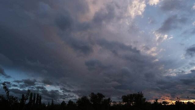 Magnificent nature landscape, little grey clouds moving fast against the blue sky. Last golden rays of the sun above the Great Hungarian Plain on a windy evening. Sunset time with amazing lights.