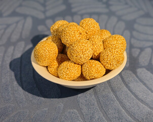 A golden sesame sweet ball glistens under soft lighting, highlighting its rich texture and perfect roundness. The toasted sesame seeds create a crunchy shell, encasing a sweet and delightful filling. 
