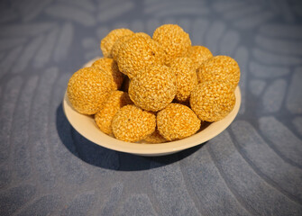 A golden sesame sweet ball glistens under soft lighting, highlighting its rich texture and perfect roundness. The toasted sesame seeds create a crunchy shell, encasing a sweet and delightful filling. 