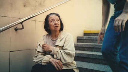 Female volunteer talks with lonely homeless woman sitting on stairs, support
