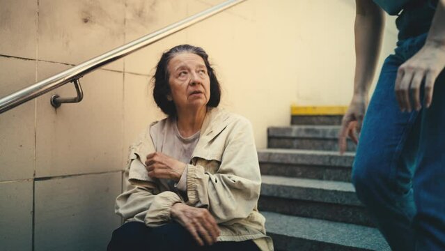 Female volunteer talks with lonely homeless woman sitting on stairs, support