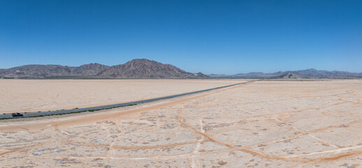 Classic panorama view of an endless straight road running through the barren scenery of the American Southwest. Extreme heat haze on a beautiful hot sunny day with blue sky in summer