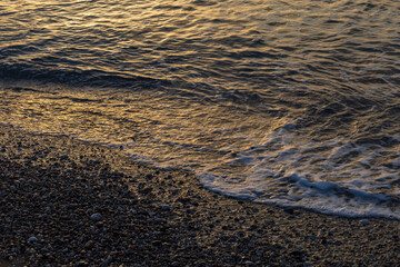 The waves of the sea wash the shore of the pebble beach.