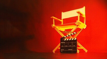 Director chair and black clapper board in red light.