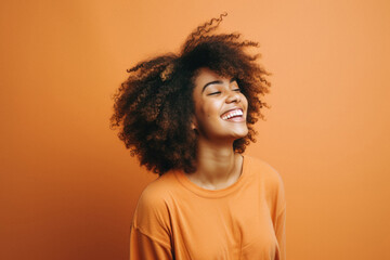 Obraz na płótnie Canvas Young pretty african american woman with curly hair posing cheerful on orange background