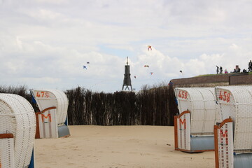 Am Strand von Cuxhaven mit Blick über die Strandkörbe zur Kugelbake mit Drachen am Himmel