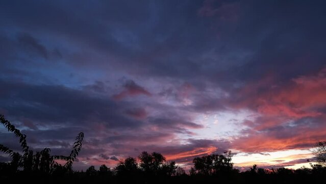 Last pink rays of the sun above the Great Hungarian Plain on a windy evening. Magnificent nature landscape, colourful clouds moving against the sky. Real time sunset with beautiful warm lights.