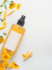 Natural yellow flowers perfume spray bottle with branding mock up on white background. Top view....