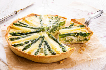 Traditional French vegetable tarte with green and white asparagus served as close-up on brown backing paper
