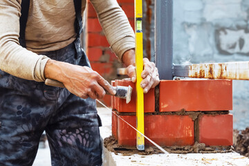 professional construction worker, industrial mason  laying bricks, building fence on industrial site