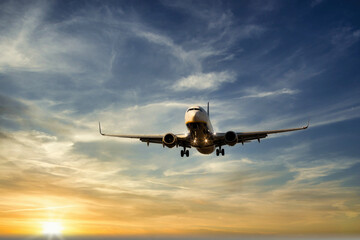The plane is flying at dawn in a sky coloured with clouds. Passenger airplane. Transport, travel and holidays