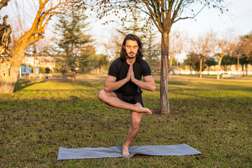 Man Practicing a Balance Pose as Part of His Outdoor Yoga Training at Sunset in a Park.