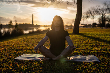Sunset yoga with the Om Pose. Doing Yoga Outdoors. Meditation - obrazy, fototapety, plakaty